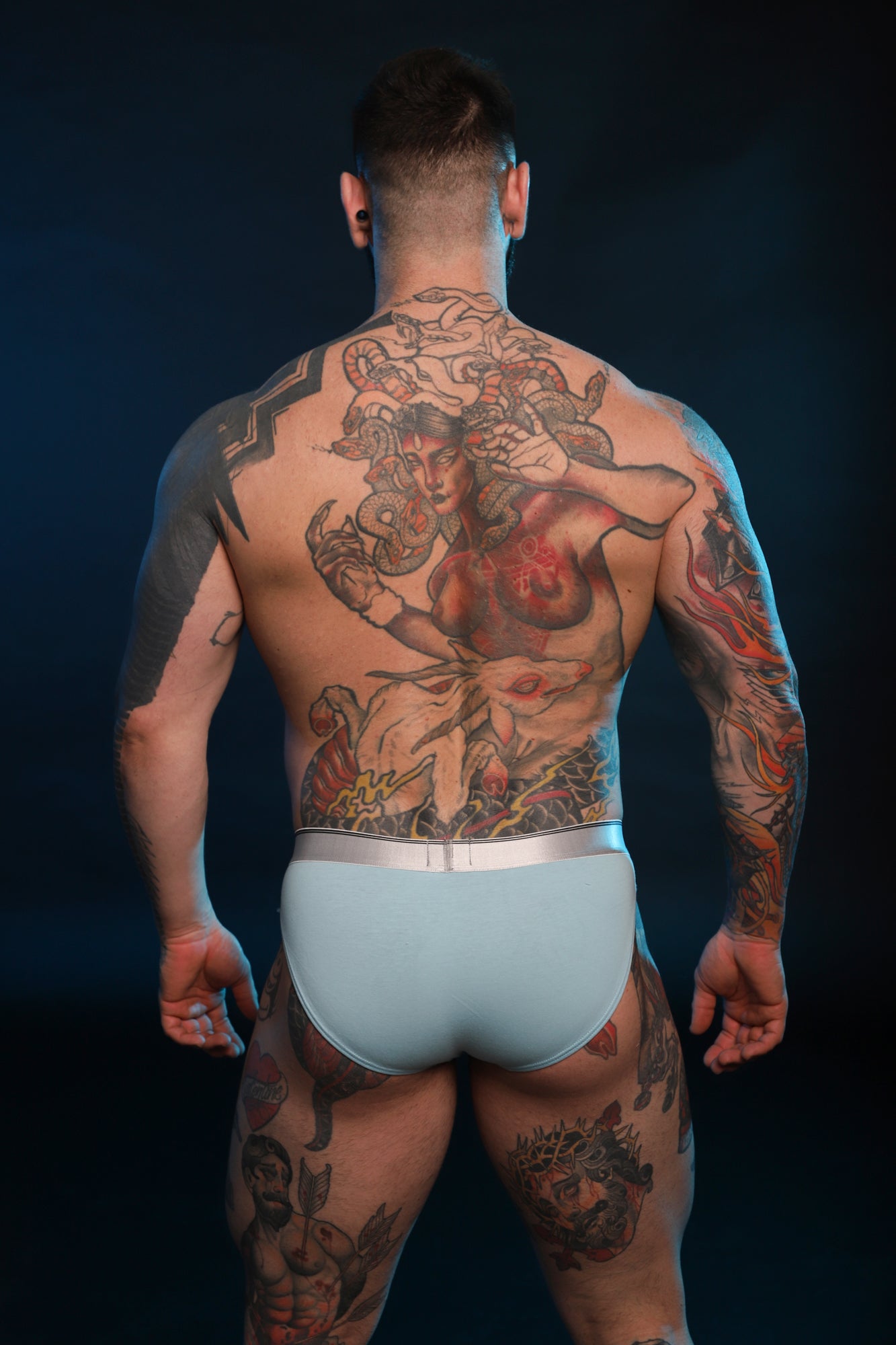 A photo of the back of a model wearing blue Y2K Brief's by Twisted Beast.